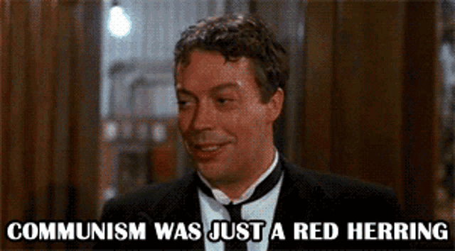 a man in a suit and tie is smiling with the words communism was just a red herring below him