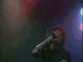 a man is singing into a microphone on a stage while wearing a hat .