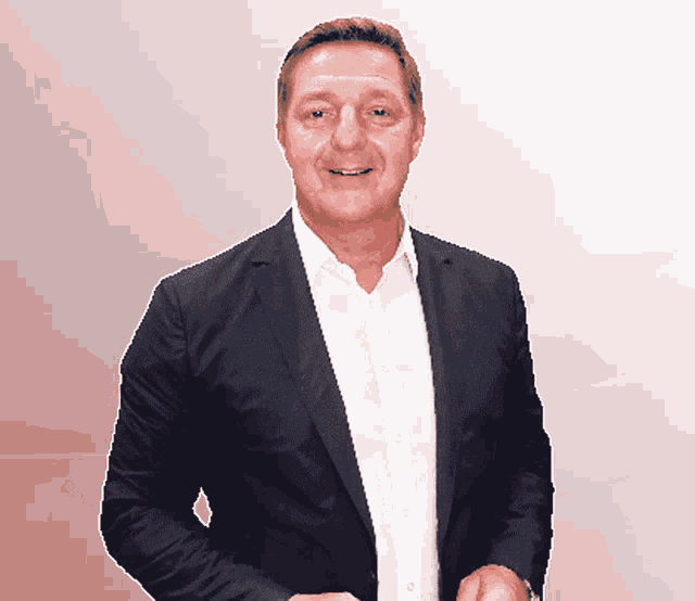 a man wearing a suit and white shirt is smiling