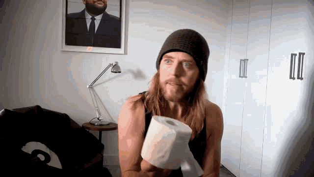 a man holding a roll of toilet paper in front of a picture of ice cube