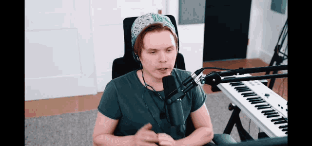 a man wearing headphones and a bandana sits in front of a microphone