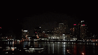 a night time view of a city with a river in the foreground and a few buildings lit up