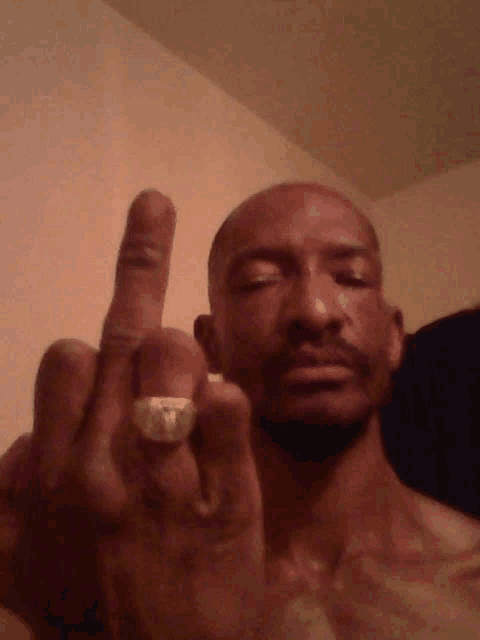 a man without a shirt is giving the middle finger