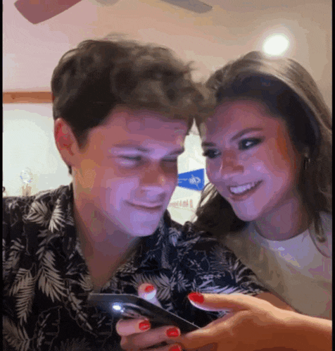 a man and a woman are looking at a cell phone