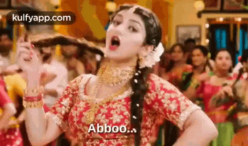 a woman in a red dress is dancing in front of a crowd of people and making a funny face .