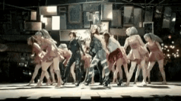a group of women are dancing on a stage in a dark room .
