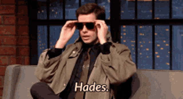 a man is sitting on a couch wearing sunglasses and saying hades