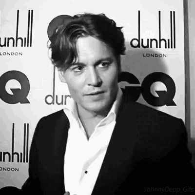 a man in a suit stands in front of a dunhill sign