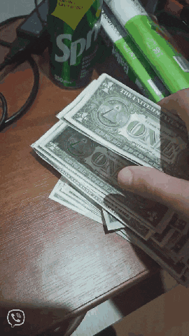 a can of sprite sits on a table next to a stack of one dollar bills