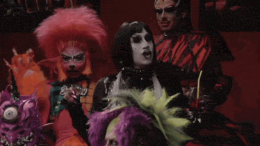 a drag queen with a candy cane in her mouth is standing next to another drag queen