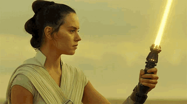 a woman holding a yellow light saber in her hand
