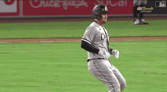 a baseball player wearing a helmet and gloves is running on a baseball field .