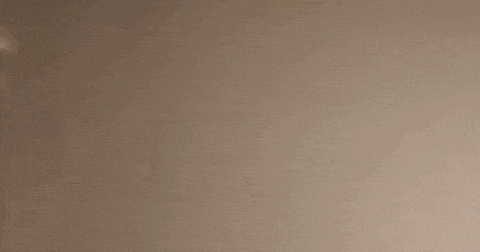 a man with a beard is standing in front of a white wall and looking at the camera .