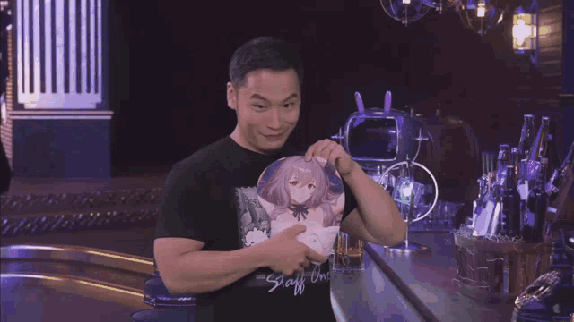 a man in a black shirt with a picture of a girl on it holds a pillow