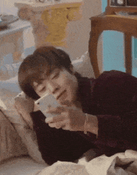 a man is laying in bed looking at his cell phone .