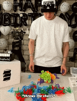 a man is sitting at a table with a bunch of toys on it and throws the chairs .