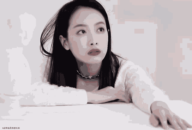 a woman wearing a choker and a white sweater is looking up