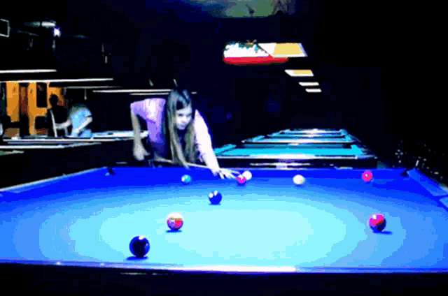 a woman playing pool in a pool hall