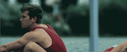 a man in a red tank top is sitting next to a woman in a red bikini .