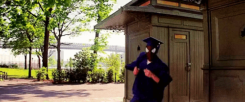 a man in a graduation cap and gown is standing in front of a shed