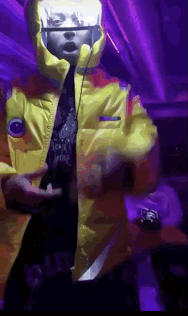 a person wearing a yellow jacket with a hood is standing in front of a purple background .