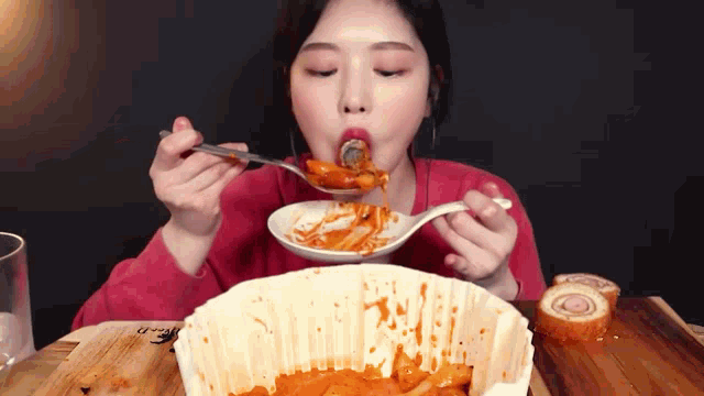 a woman is eating food from a bowl with a spoon in her mouth