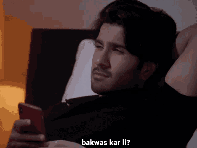 a man laying on a bed looking at his phone with the words bakwas kar li