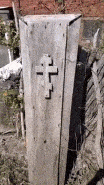a wooden coffin with a cross on it is sitting on the ground .