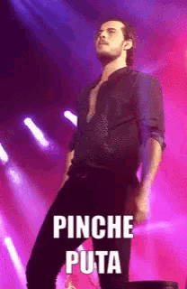 a man in a black shirt stands on a stage with the words pinche puta written on the bottom