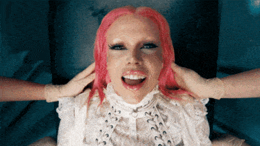 a woman with pink hair and a white lace shirt is being examined