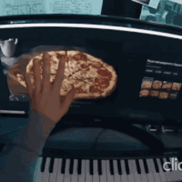 a person is playing a keyboard and holding a pizza in their hand