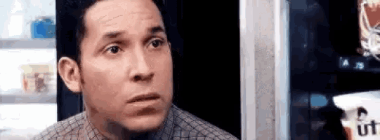 a man is standing in front of a vending machine making a funny face .