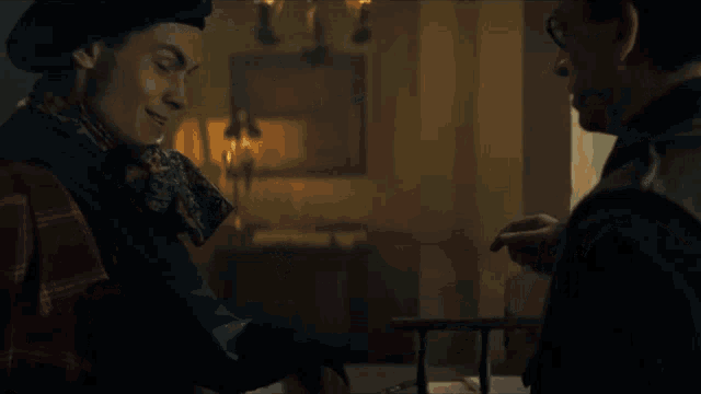 a man wearing a beret and a scarf talks to another man