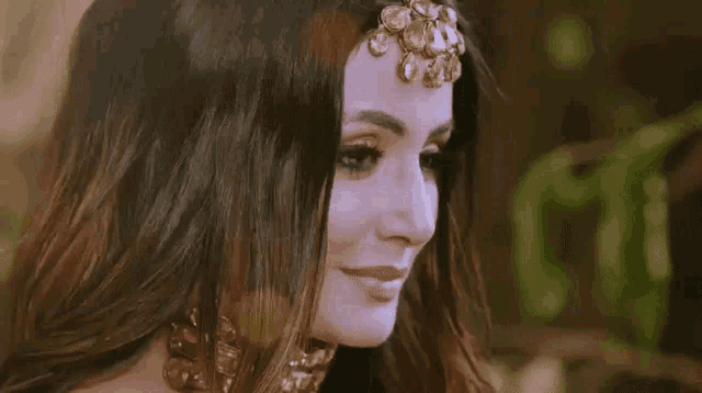 a close up of a woman 's face with a nose ring and a necklace .