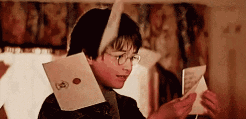 harry potter is reading a letter from harry potter while wearing glasses .