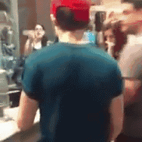 a man wearing a blue shirt and a red hat stands in front of a mirror .