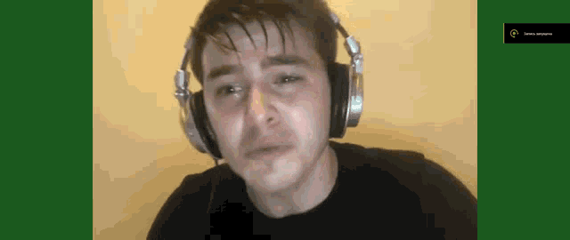 a man is wearing headphones and crying while looking at the camera .