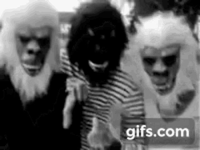 a group of people wearing masks and wigs are standing next to each other in a black and white photo .