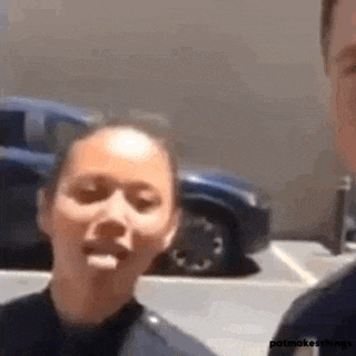 a woman in a police uniform is sticking her tongue out in a parking lot .