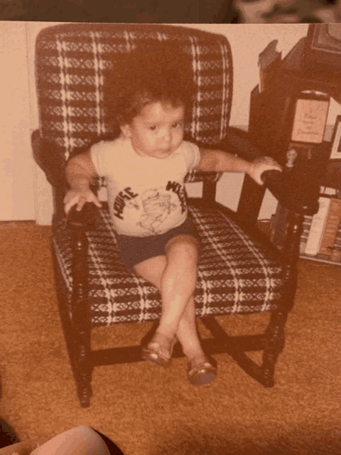 a young boy wearing a shirt that says mouse on it sits in a chair