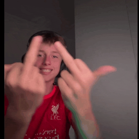 a young man wearing a red lfc shirt shows his middle finger