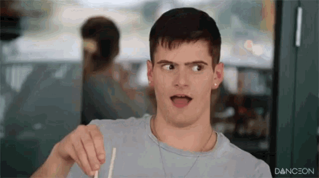 a man is holding a straw in his hand and making a face .
