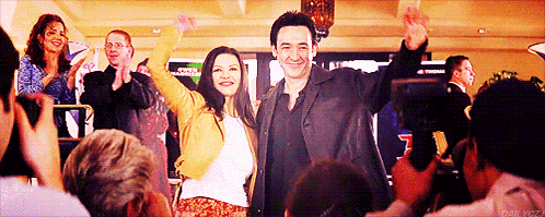 a man and a woman standing in front of a crowd with their hands in the air