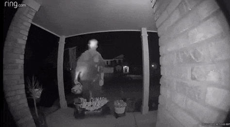 a man is standing on a porch in front of a house at night holding a lantern .