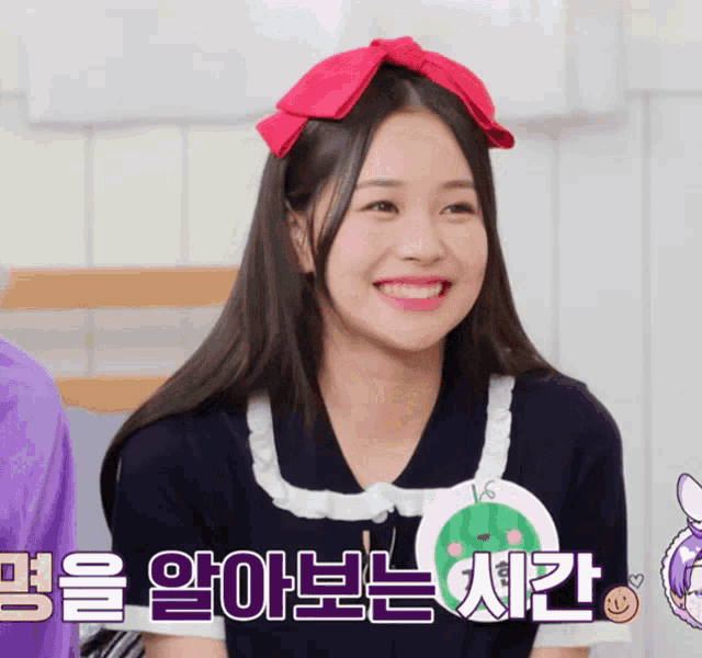 a girl wearing a pink bow on her head smiles in a video