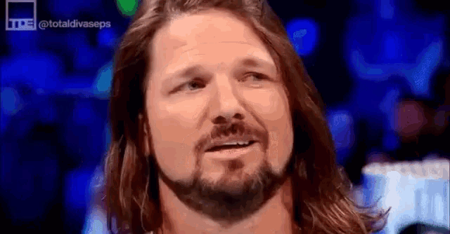 a wrestler with long hair and a beard is smiling .