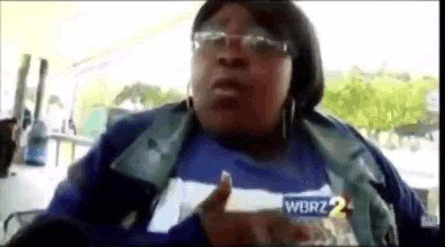 a woman wearing glasses and a blue and white striped shirt is talking to a camera .