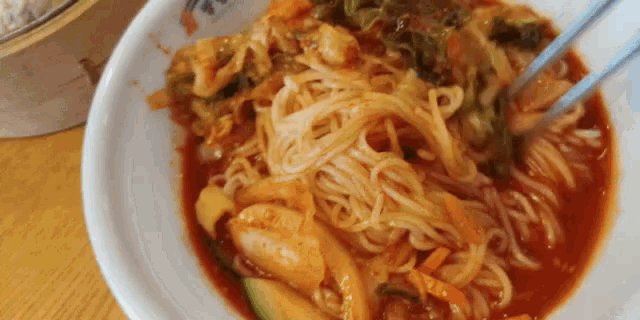 a close up of a bowl of noodles with chopsticks in it .