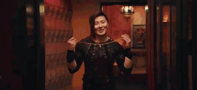 a woman in a black dress is holding a chain in her hands .