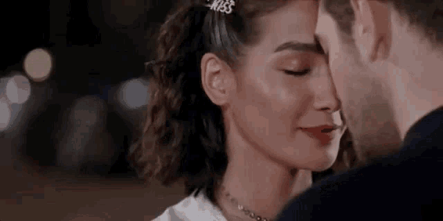 a man and a woman are kissing and the woman is wearing a necklace .